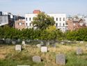 small headstones arrayed on the steep hill at the northern end of Greenwood cemetery adjoining low-rise apartments